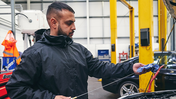 Technician checking engine oil dipstick