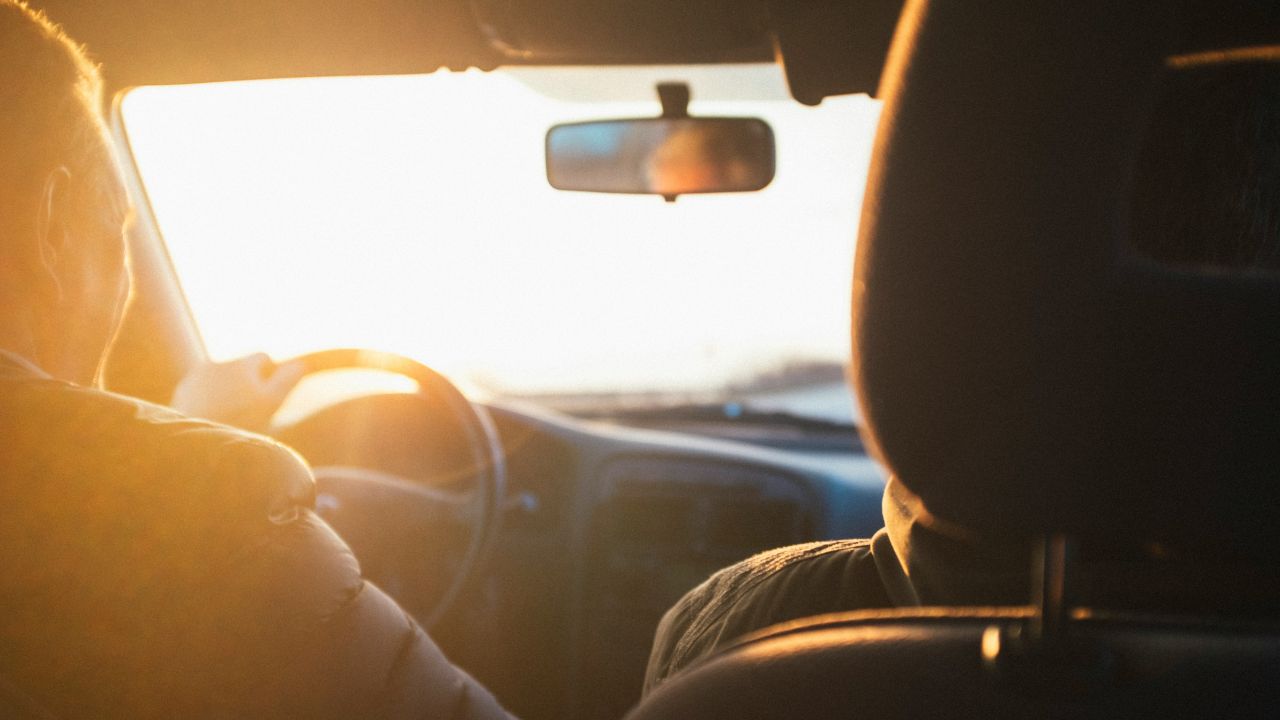 Man driving a car with the sun shining through the vehicle's windshield