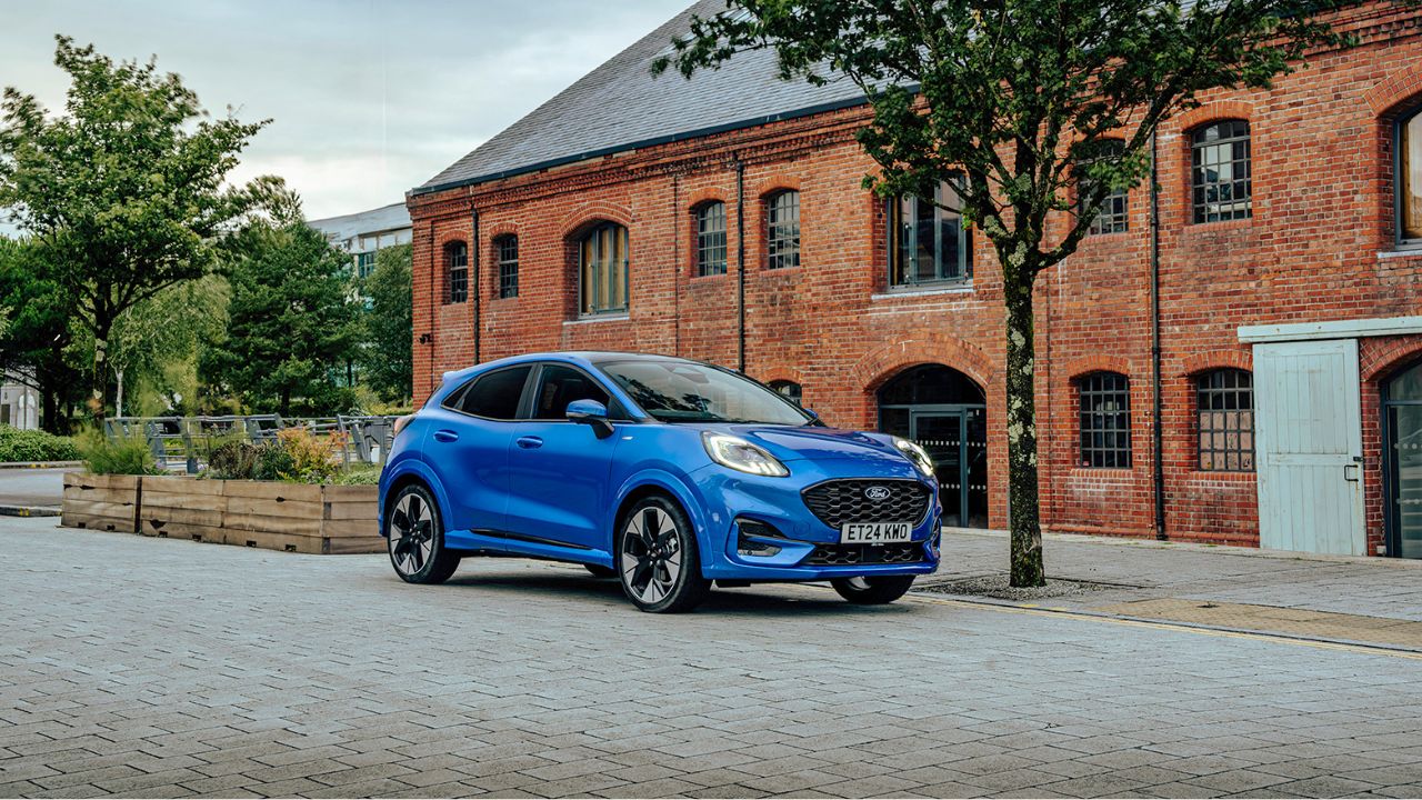 Blue Ford Puma parked in front of a red brick wall building