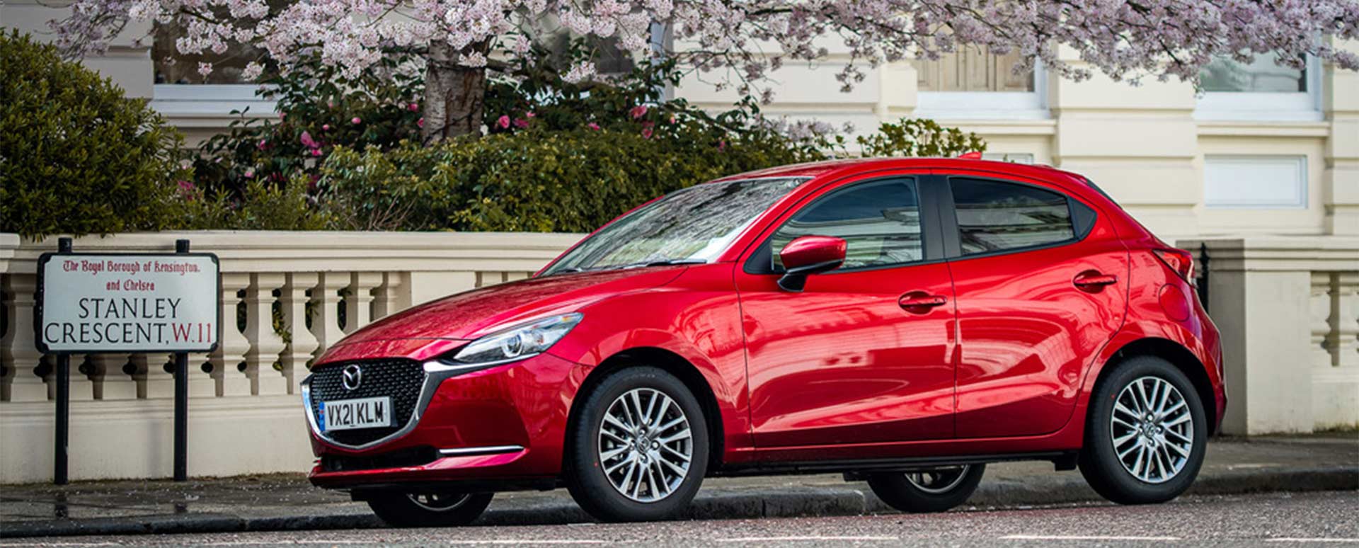 Red Mazda2 parked under a tree