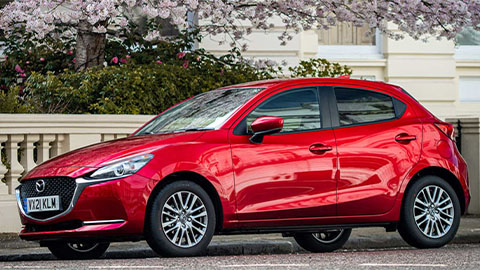 Red Mazda2 parked under a tree