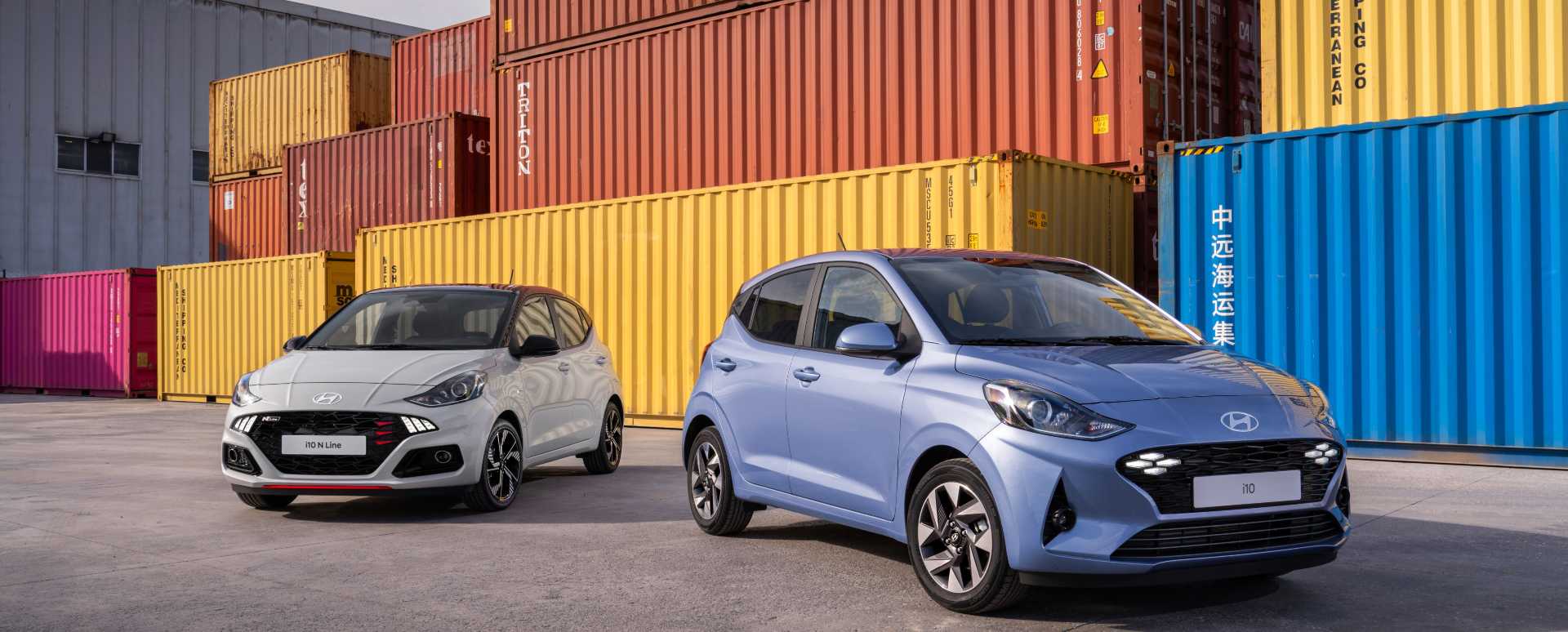 Blue Hyundai i10 pair front with shipping containers behind