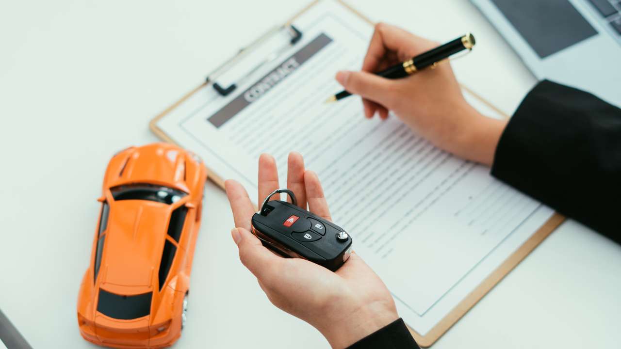 Person holding a car key  whilst signing a contract