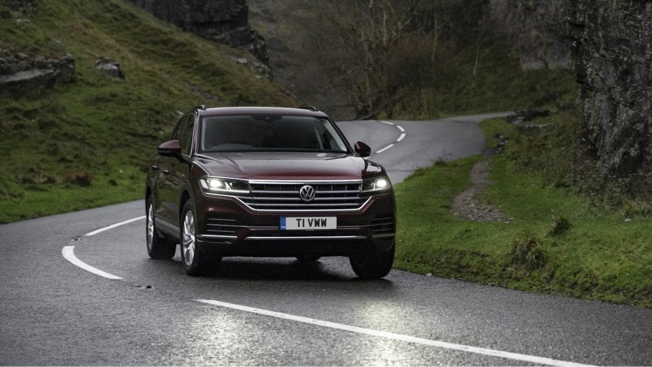 Burgundy Volkswagen Touareg driving on a road in the country side