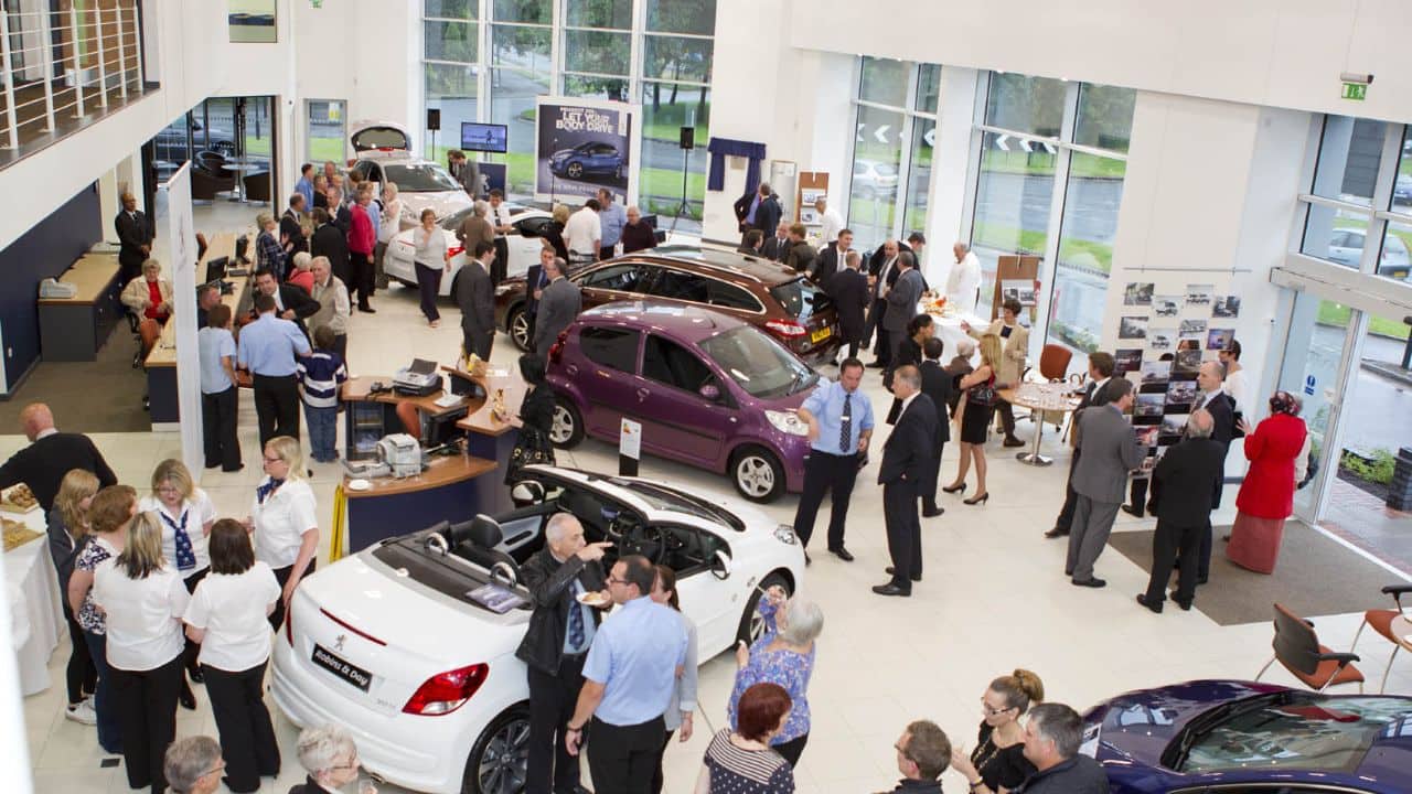 Peugeot dealership with a lot of people in the showroom looking at cars