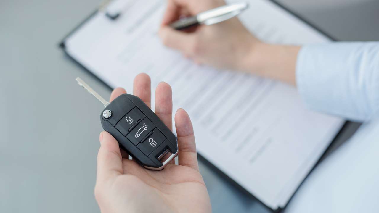 Man signing a contract whilst holding a car key