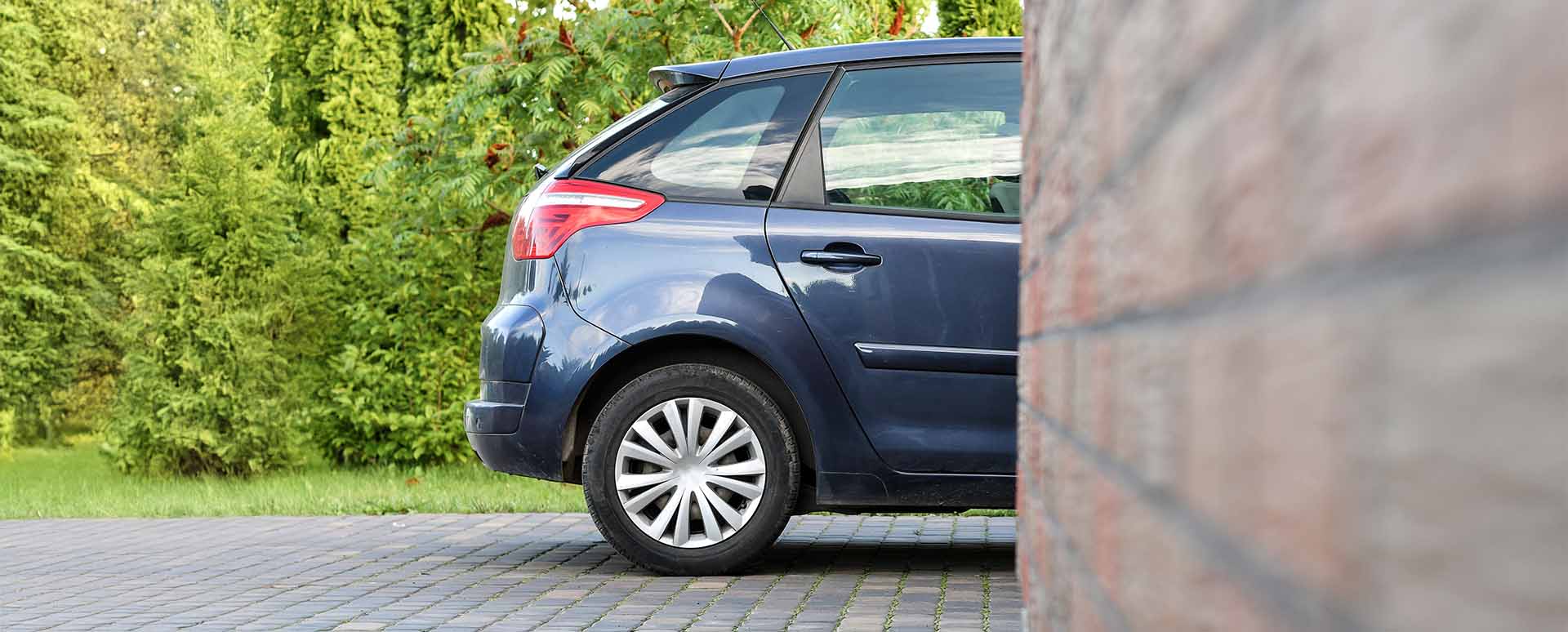 Rear Half of Car Parked in Driveway With Front Half Covered By Wall