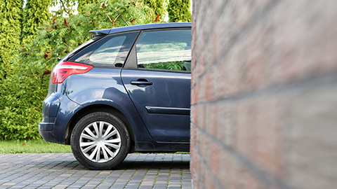 Rear Half of Car Parked in Driveway With Front Half Covered By Wall