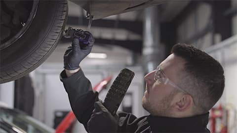 Vehicle technician checking over the tread depth of the tyre on a car