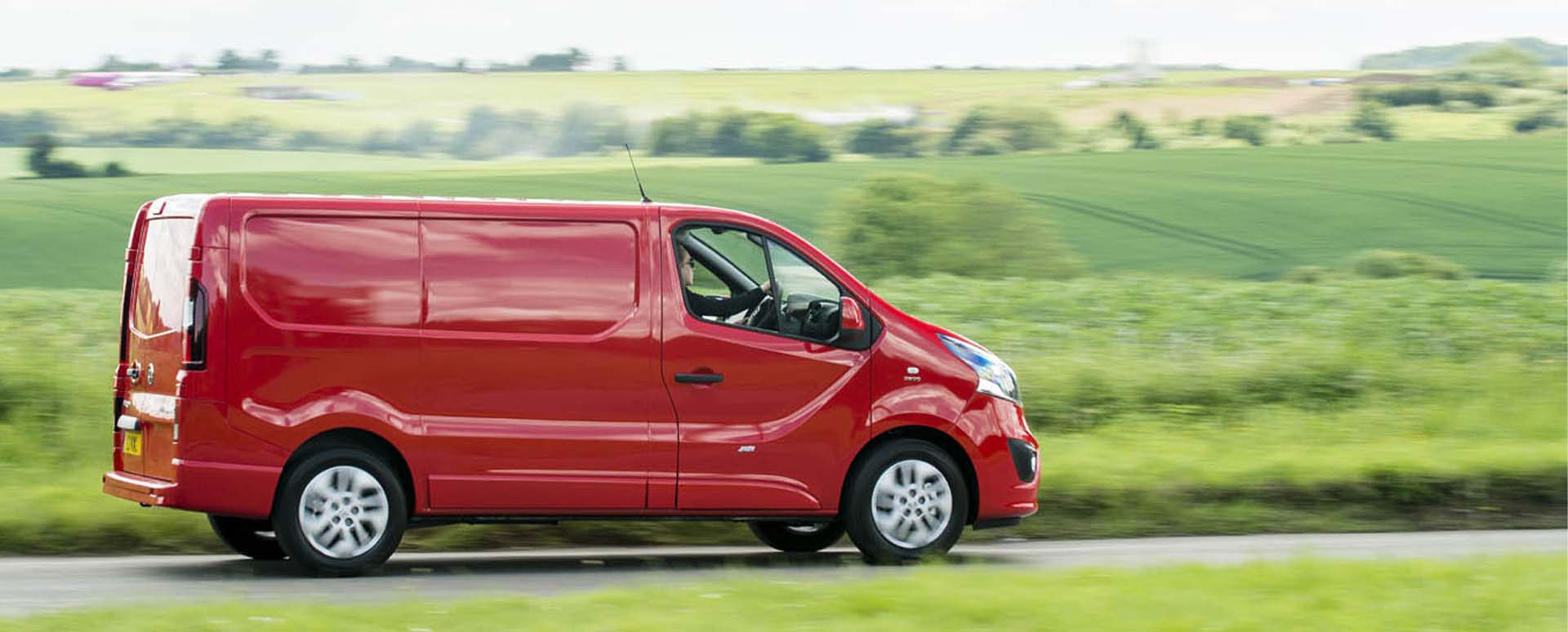 Red Vauxhall Vivaro, side shot, driving in the countryside