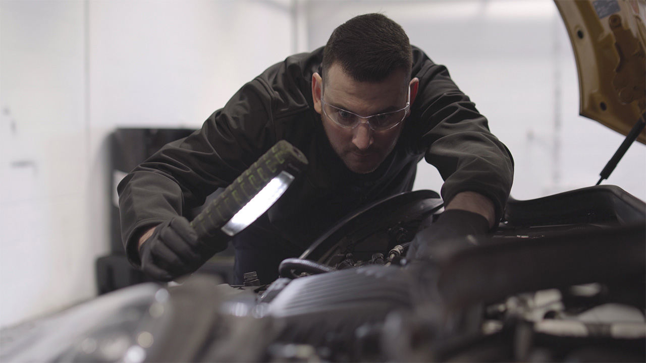 MOT Technician inspecting a vehicle's engine bay