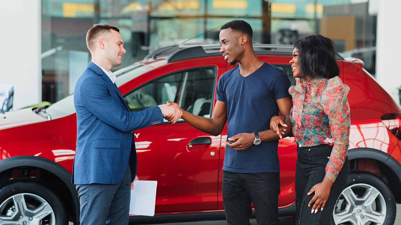 Car Salesman Shaking Hands With Man in Dealership