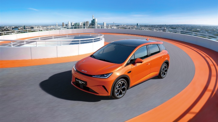 BYD Dolphin G DM‑i driving on rooftop car park with city skyline