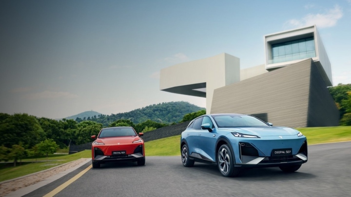 Two Changan Deepal S07 electric SUVs driving on a modern road with contemporary architecture in the background