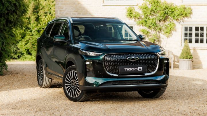 A dark green Chery Tiggo 8 car parked outside a country house.