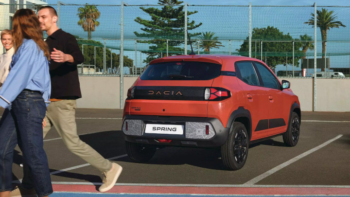 People Walking In Front Of Red Dacia Spring