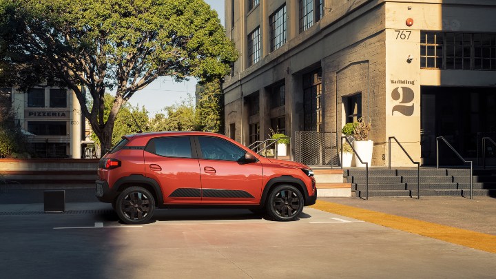 Dacia Spring orange side parked near warehouse