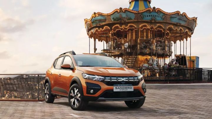 Orange Dacia Sandero parked in front of a carousel