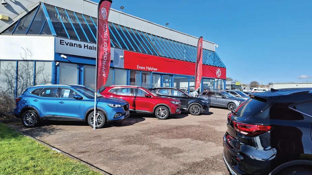 Exterior shot of an MG dealership in Grantham, with cars parked out front the main entrance, and the MG flag flying above