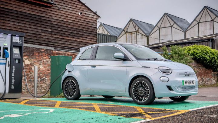 Light blue Fiat 500 being charged by a house