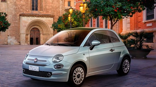 Silver Fiat 500 parked in front of a church made of bricks
