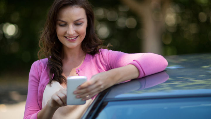 Woman Using Smartphone Next to Car