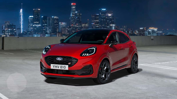 Red Ford Puma ST Mild Hybrid Parked On Roof of Building at Night with Tall Buildings in the Background