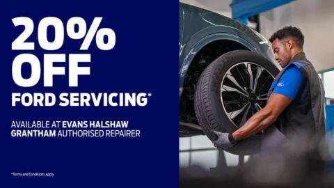 Man holding a car wheel whist a car is lifted up