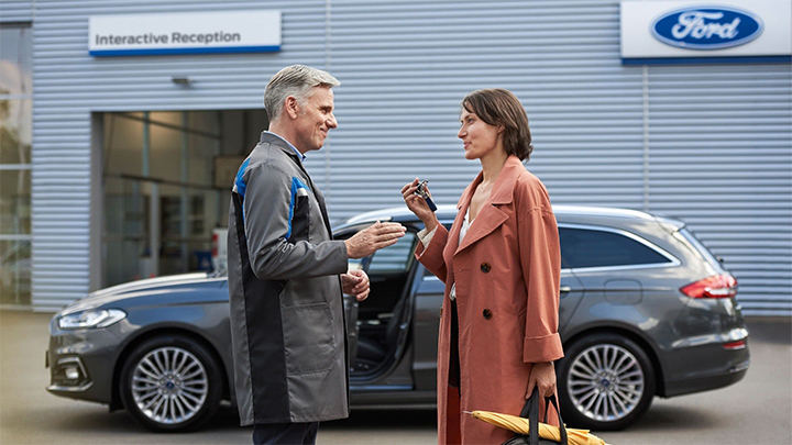 A Ford Service Advisor handing over the keys to a customer outside a dealerships