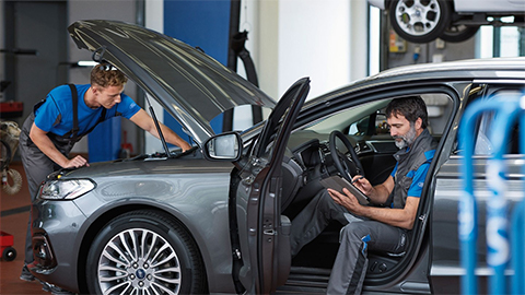 Two Ford technicians working on a Ford Mondeo in a workshop