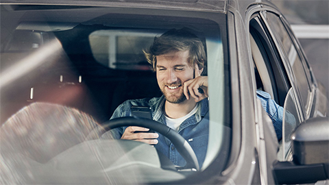 Customer sitting inside a Ford, sitting on his phone