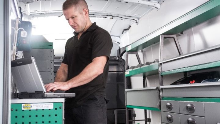Man checking his laptop in a van