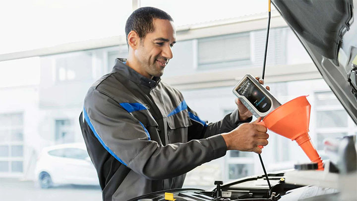 Ford technician topping up a car's fluids