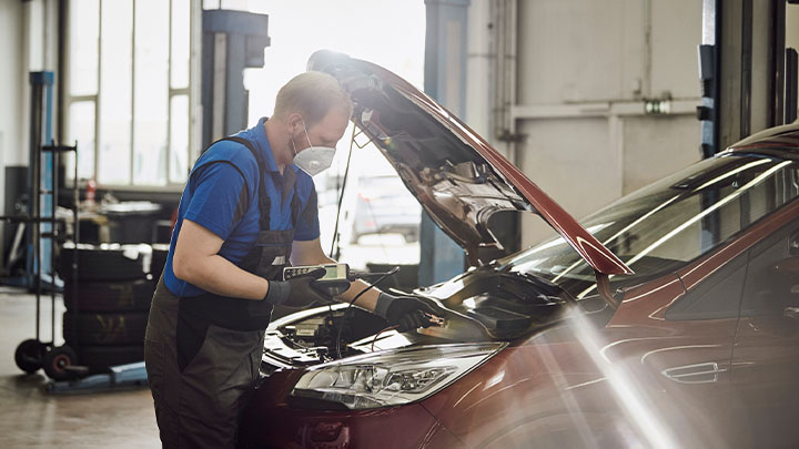 Technician changing car battery on Ford vehicle