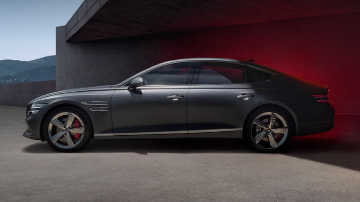 Blue Genesis G80 parked halfway into a garage with red ambient lighting