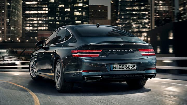 Blue Genesis G80 driving into a city at night