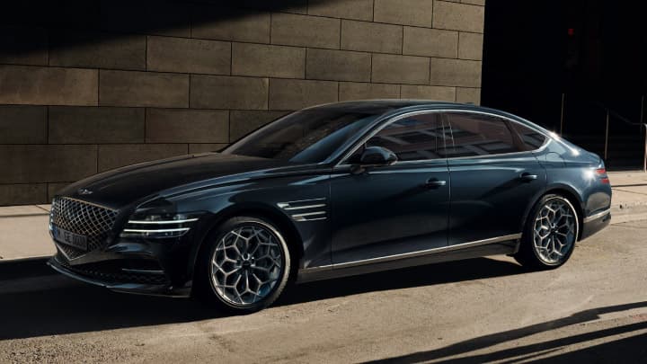 Blue Genesis G80 parked next to a large building
