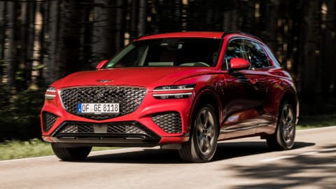 Red Genesis GV70 driving on a country road