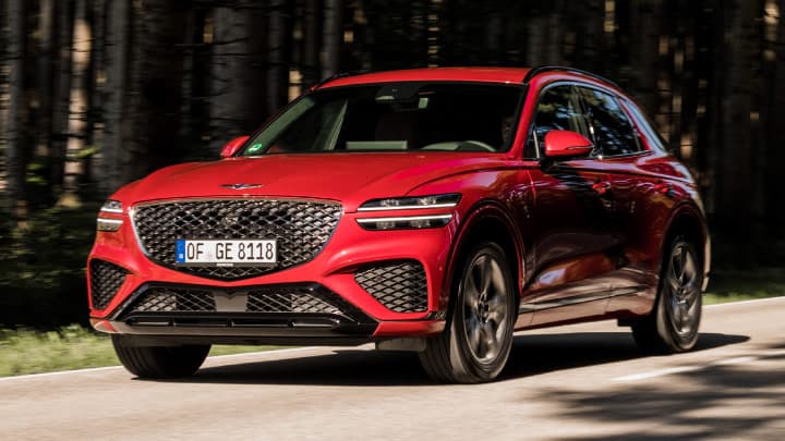 Red Genesis GV70 driving on a country road
