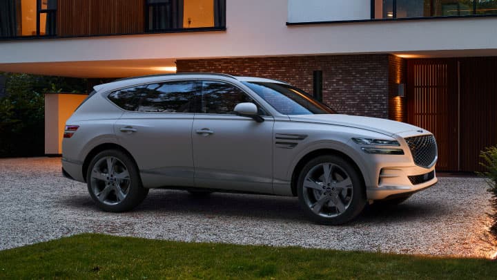 White Genesis GV80 parked outside a large modern house