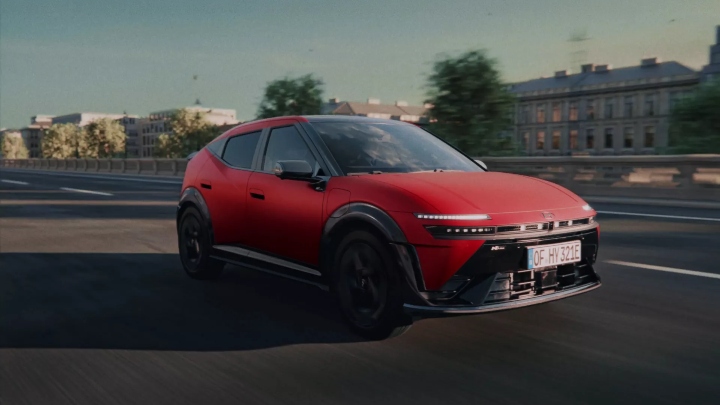 Red Hyundai IONIQ 3 driving through city, front three-quarter view
