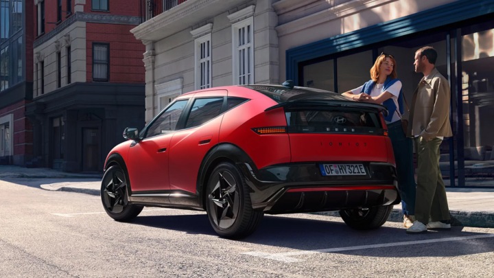 Hyundai IONIQ 3 parked in city street, rear three-quarter view in red