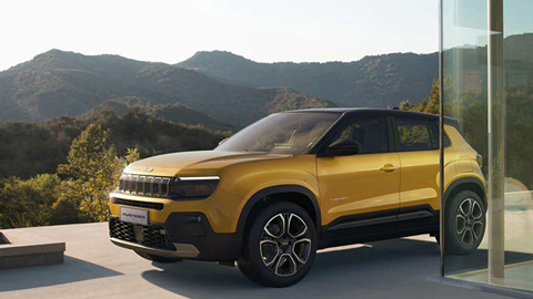 Front quarter lifestyle shot of a yellow Jeep Avenger parked with a mountain landscape behind