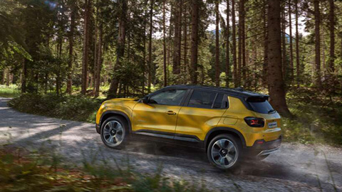 Rear quarter action shot of a yellow Jeep Avenger driving through a woodland and down a track