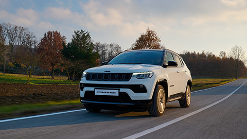 White Jeep Compass driving down a country road
