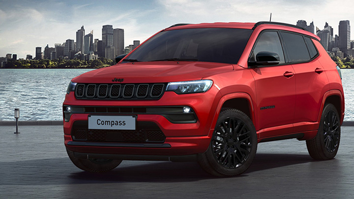 Red Jeep Compass studio shot with a city in the background