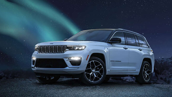 Front quarter shot of a white Jeep Grand Cherokee with the northern lights added to the background