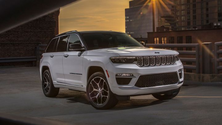 White Jeep Grand Cherokee parked on a bridge with a city skyline in the background