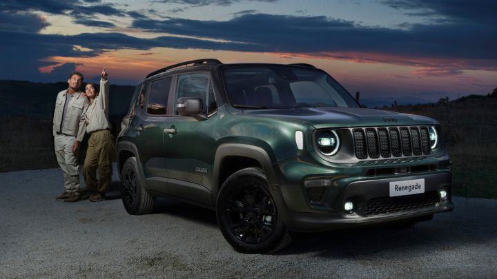 A couple looking at the stars while standing beside a green Jeep Renegade