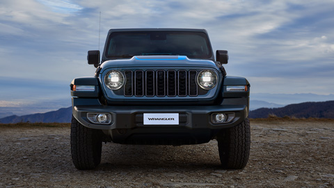 Front end shot of a blue Jeep Wrangler with a desert background